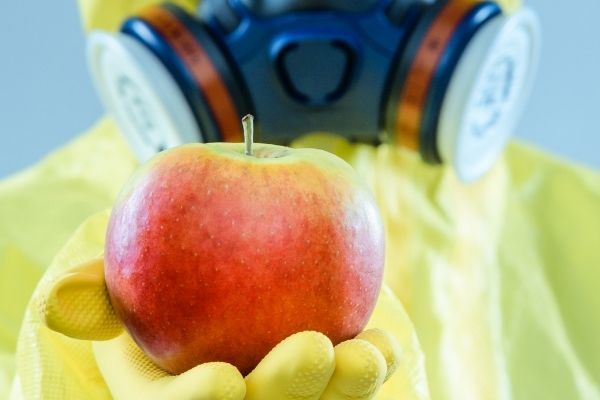 man in yellow chemical suit holding a red apple for gmo information you should know