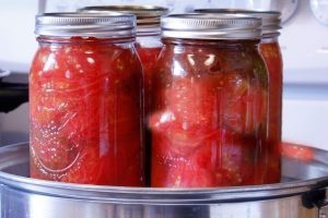 tomatoes in glass jars inside a pressure canner to be used to can tomatoes