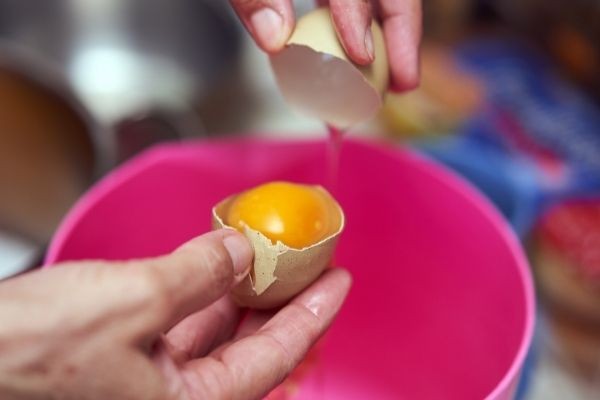egg being cracked in pink bowl for spots on fresh chicken eggs