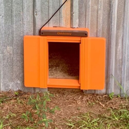 ChickCozy Automatic Chicken Coop Door exterior view as mounted on a metal sided chicken coop