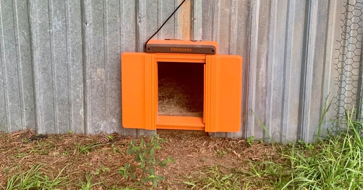 ChickCozy Automatic Chicken Coop Door exterior view as mounted on a metal sided chicken coop