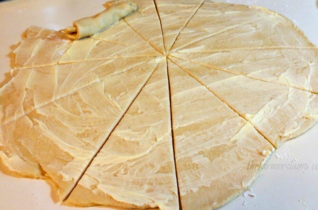 homemade crescent rolls cut and buttered ready to be rolled as part of the Homemade Crescent Rolls Recipe