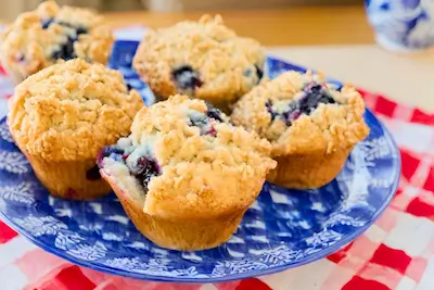einkorn blueberry muffins with struesel topping on a blue and white plate