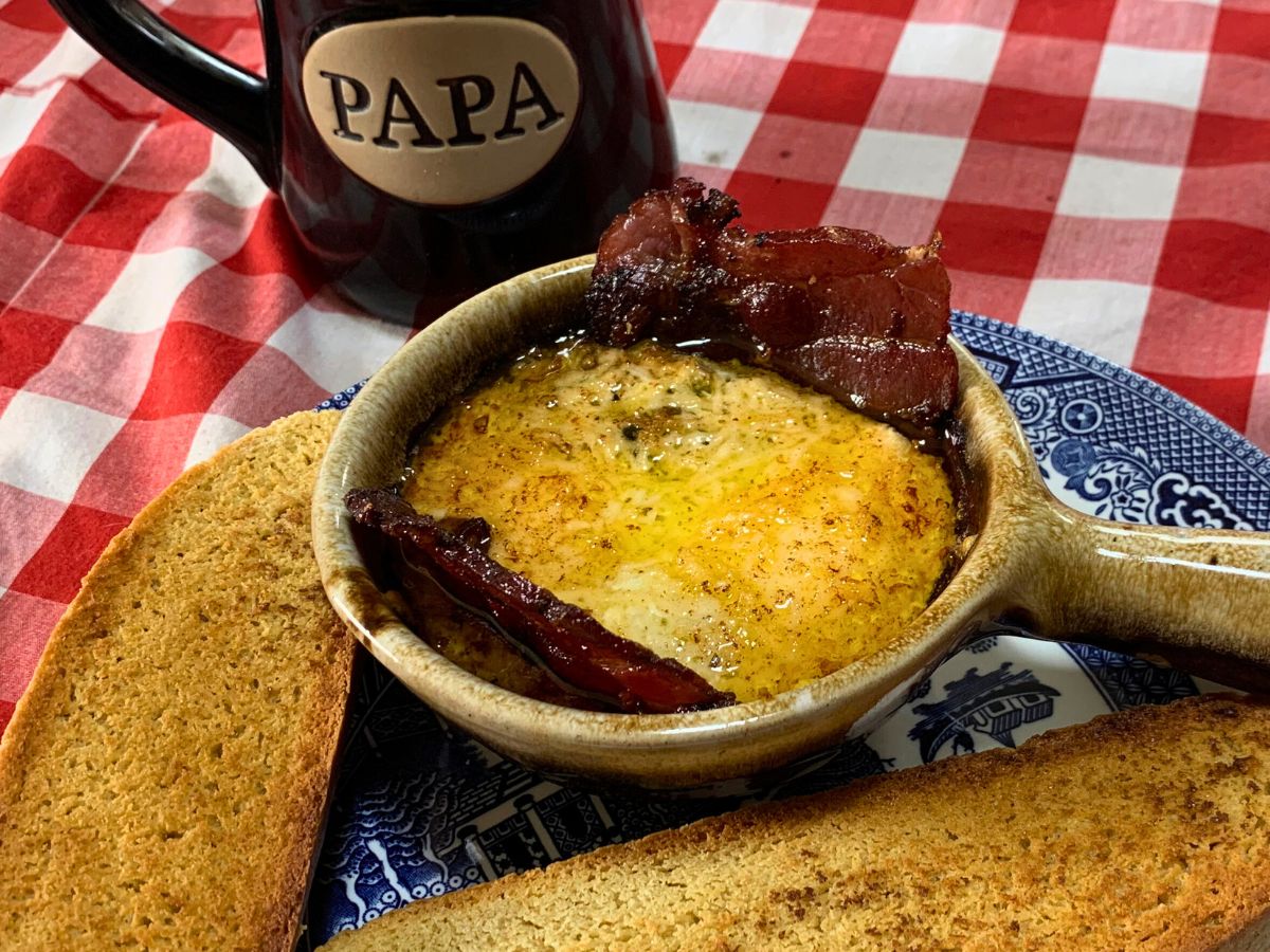 brown ceramic bowl with egg bowl recipe cooked in it sitting on a blue willow plate