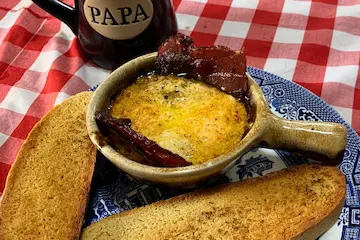 blue willow plate with a brown ceramic bowl with egg bowl recipe cooked in it with bacon and toast