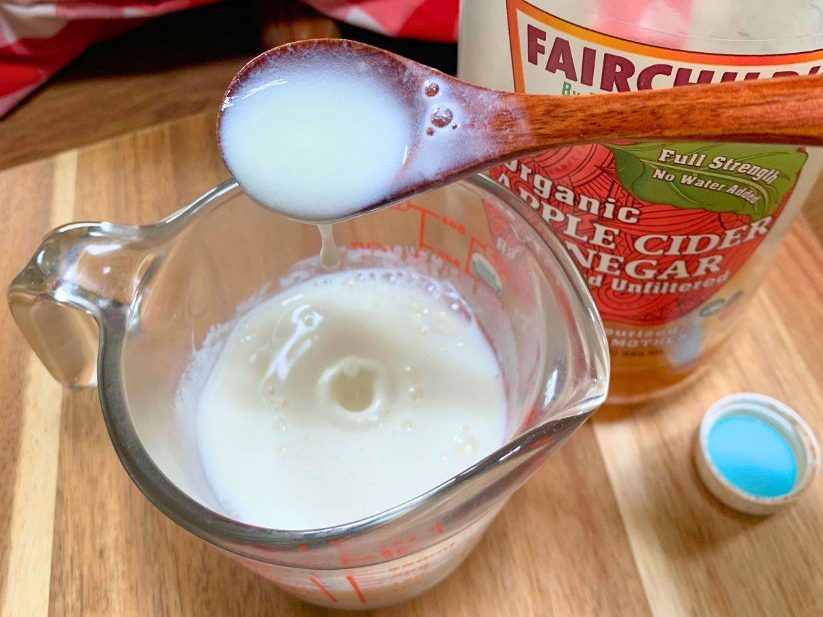 homemade buttermilk in a glass measuring cup on a wood cutting board