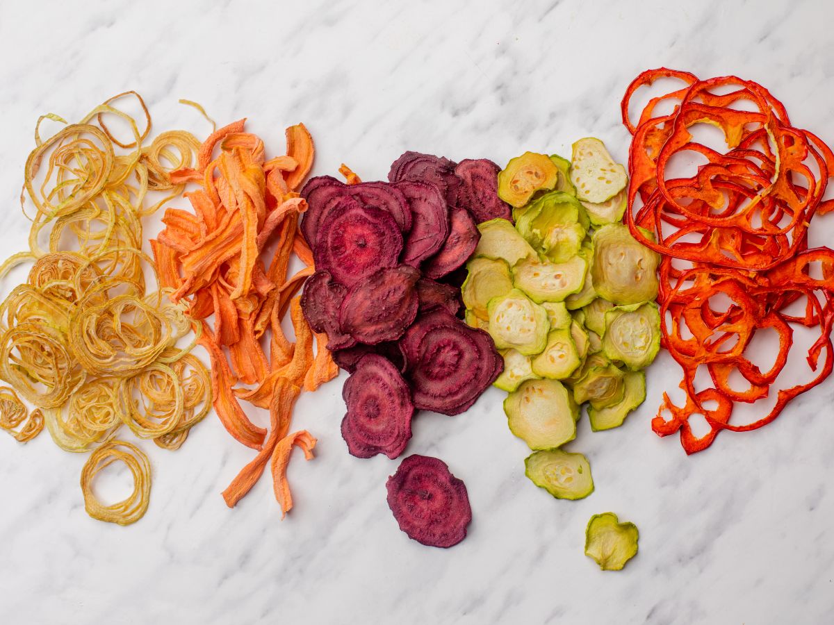 dehydrated onions carrots beats cucumbers and peppers on a marble cutting block