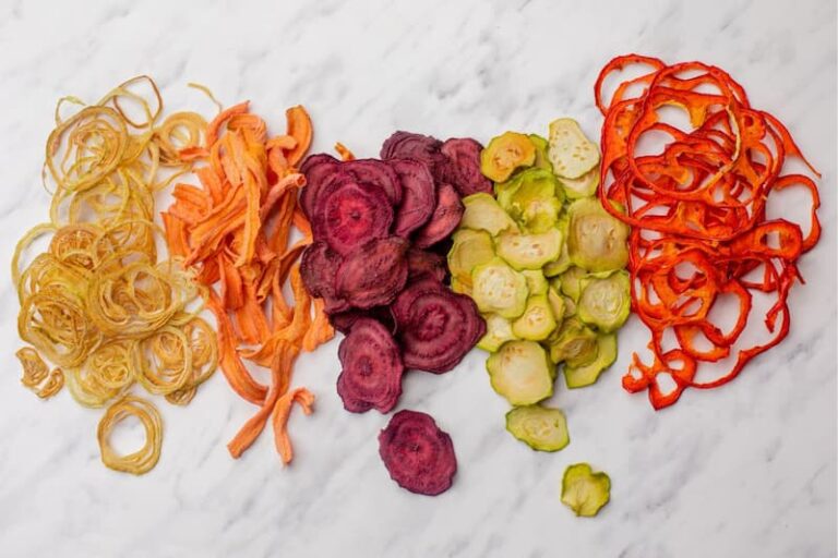 dehydrated onions carrots beats cucumbers and peppers on a marble cutting block