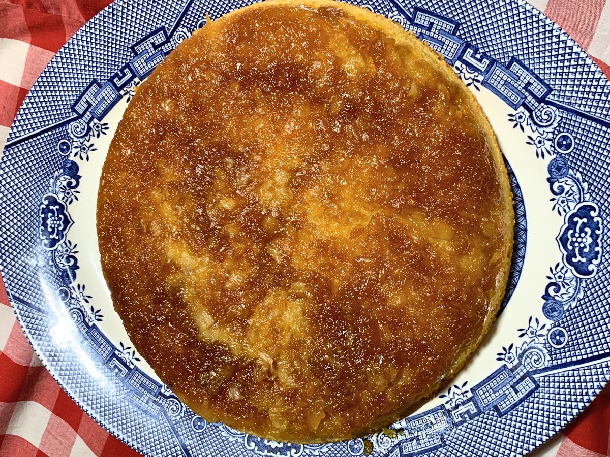 from scratch pineapple upside down cake made with crushed pineapple on a blue willow plate with a red gingham table cloth behind it