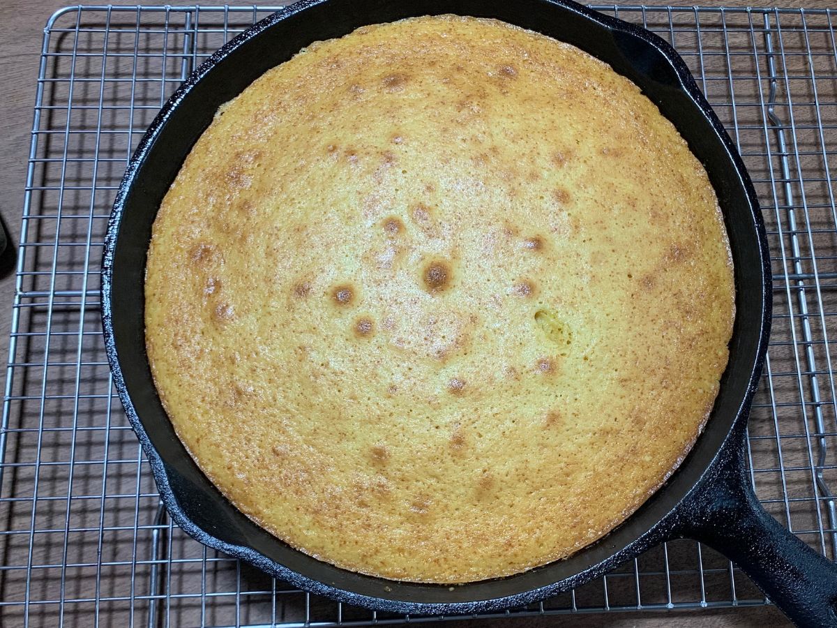 baked pineapple upside down cake in skillet cooling on a wire cooling rack 