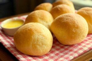 einkorn dinner rolls on a red gingham cloth with a white bowl of melted butter