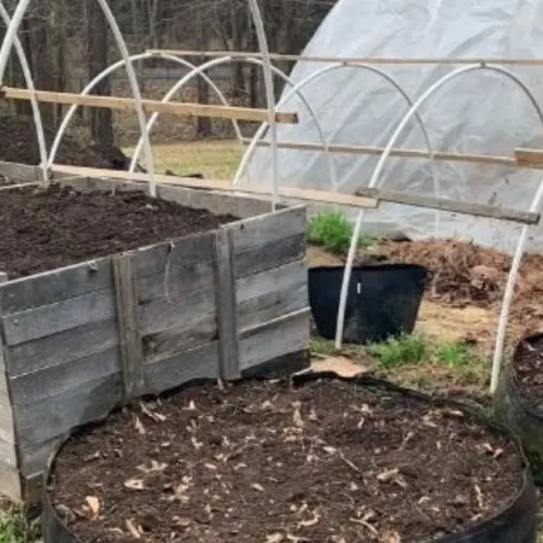 How to set up a vegetable garden - hoop house with round beds out front, waiting to be planted.