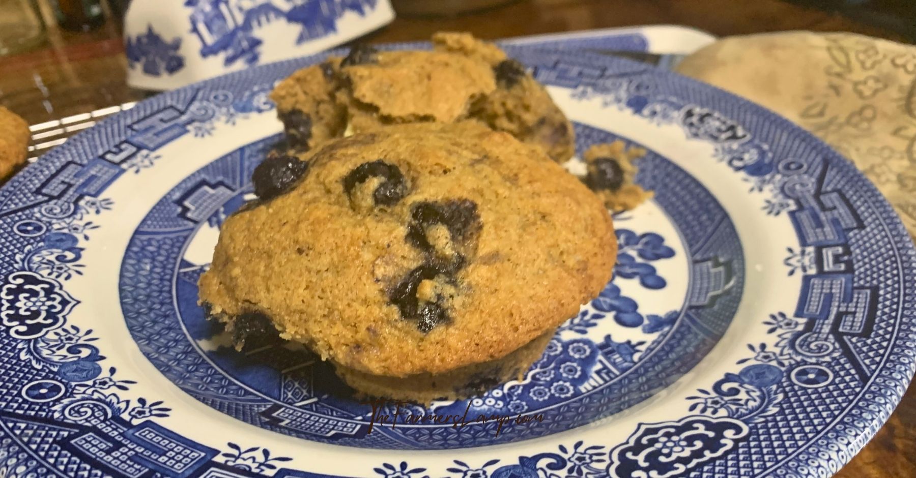 spelt flour muffins with blueberries on a blue willow plate.