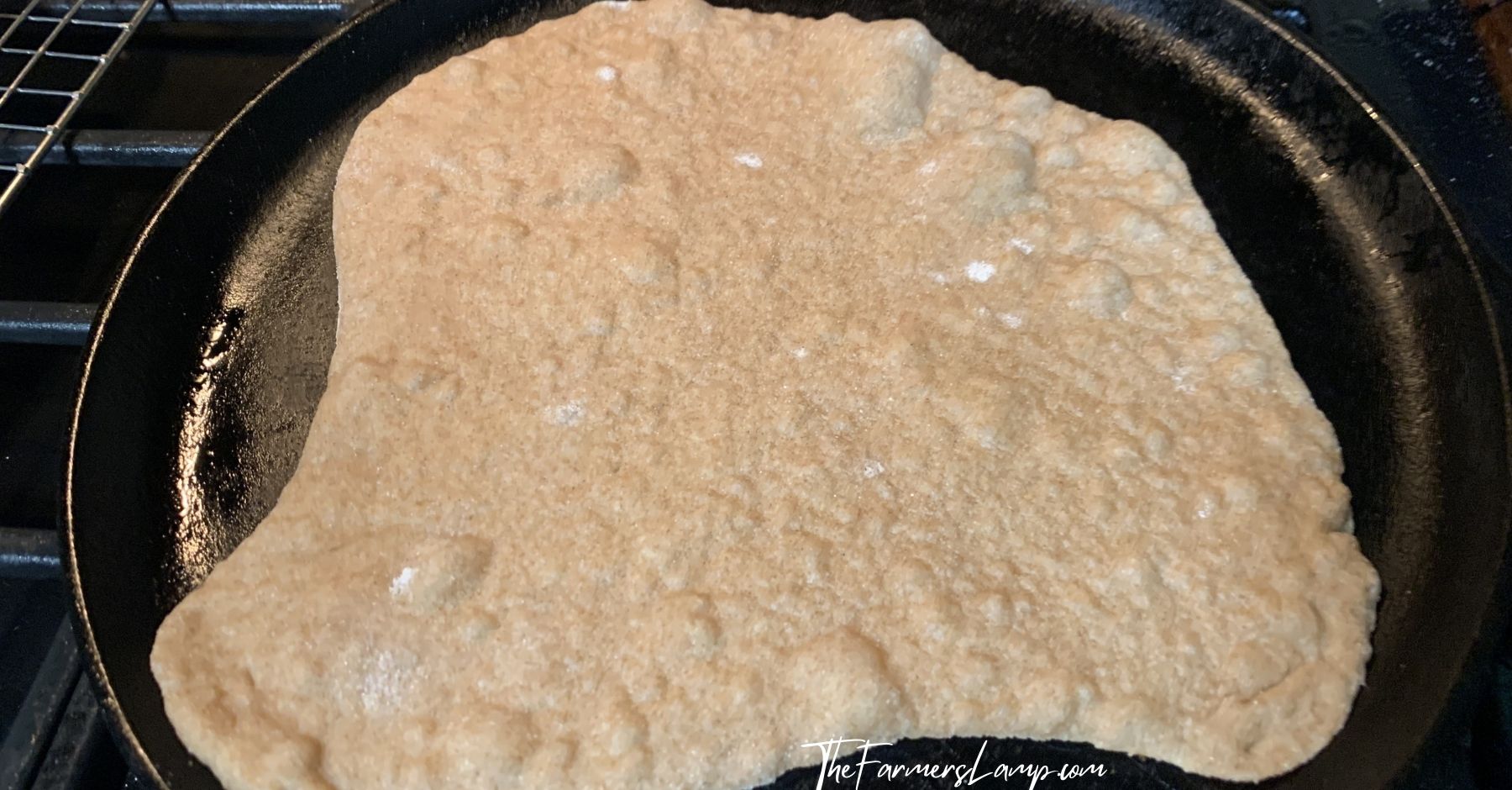 spelt flour tortillas on a cast iron skillet showing bubbles as it cooks