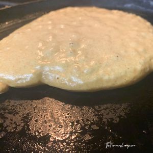 Spelt Flour Pancakes Small 2 spelt flour pancakes cooking on a cast iron griddle with sides setting showing when to flip the pancake