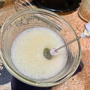 Frothy egg whites being whipped with milk frother