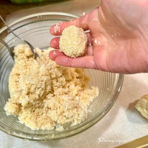 Hand holding a shaped macaroon ball ready for the pan